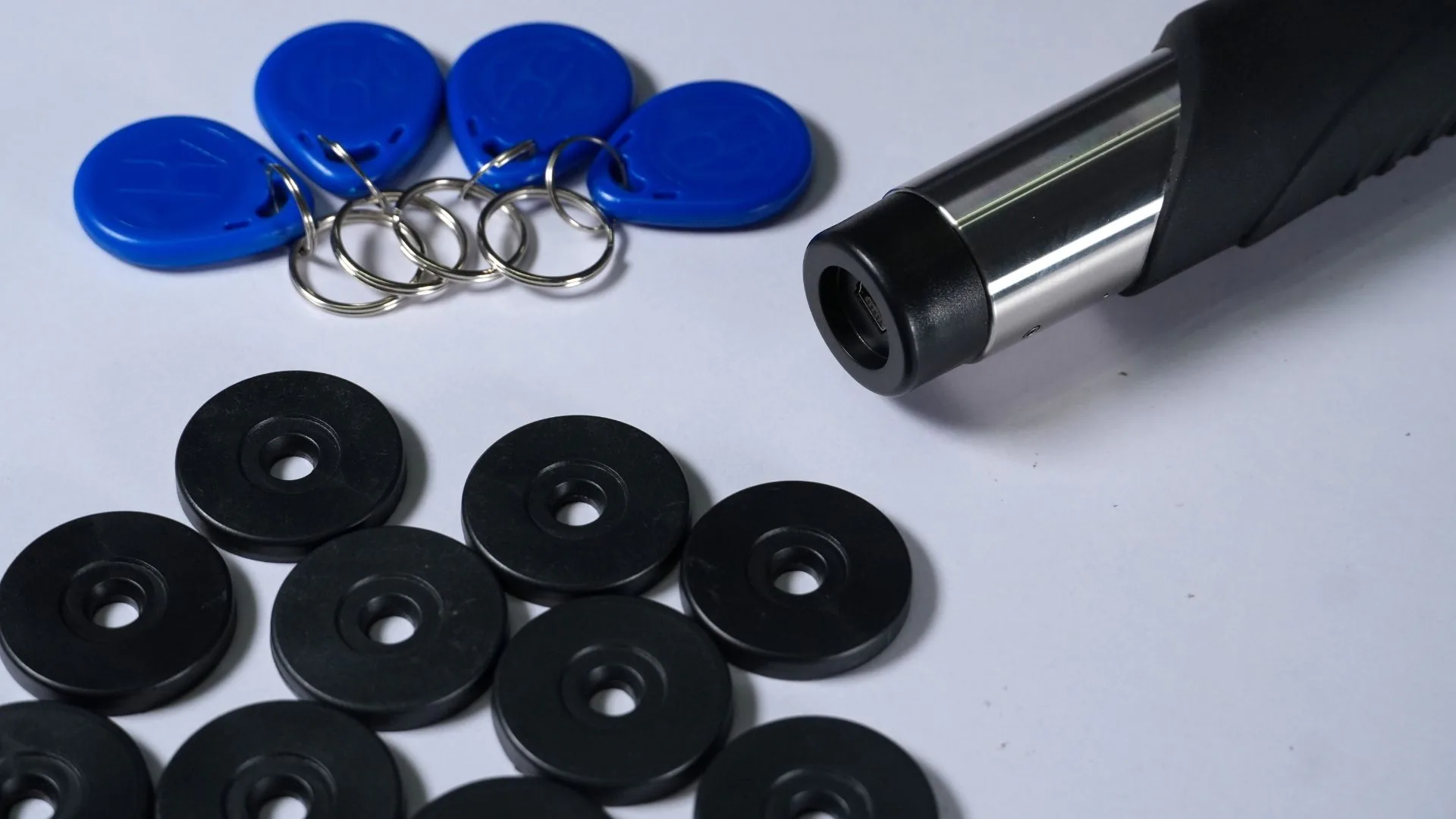 Lector portátil del control de rondas junto a sus llaveros azules y sus puntos de control negros.