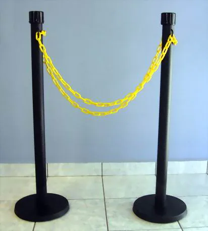 Poste con cadena plástica 10 Dos postes negros con una cadena plástica amarilla colgada entre ellos.